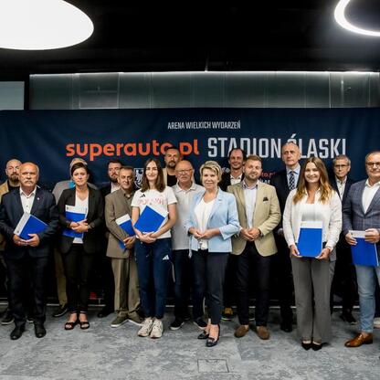 Grupa osób z wicemarszałkiem Leszkiem Pietraszkiem na ceremonii w Superauto.pl Stadion Śląski, związana z sukcesami w konkursie na finansowanie kultury fizycznej i bezpieczeństwa publicznego. (wygenerowano przez AI)