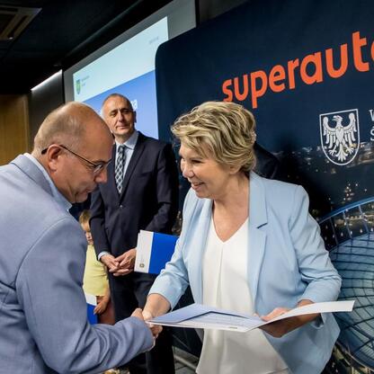 Wicemarszałek Leszek Pietraszek prezentuje certyfikat na ceremonii w Superauto.pl Stadion Śląski. (wygenerowano przez AI)