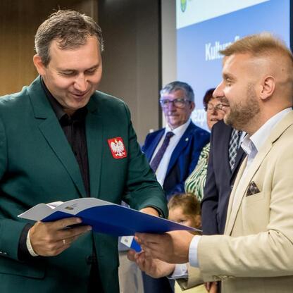Wicemarszałek Leszek Pietraszek prezentuje dokument na ceremonii w Stadionie Śląskim, wspierając działania w dziedzinie kultury fizycznej i bezpieczeństwa publicznego. (wygenerowano przez AI)