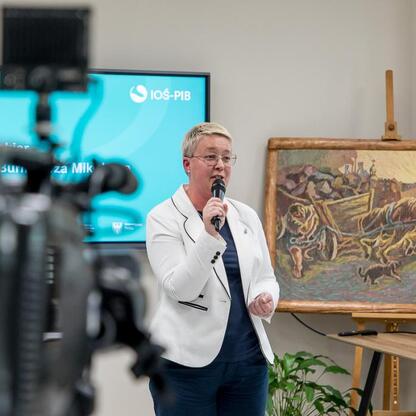 Kobieta przemawia na konferencji prasowej w Mikołowie, prezentując Regionalny Plan Adaptacji do zmian klimatu dla Śląska. (wygenerowano przez AI)