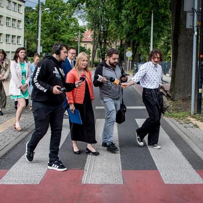 Grupa oficjalnych i dziennikarzy spaceruje przez Mikołów, omawiając plany adaptacji do zmian klimatu. (wygenerowano przez AI)