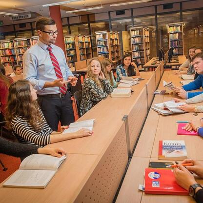 W bibliotece Śląska studenci uczestniczą w dyskusji prowadzonej przez nauczyciela. (wygenerowano przez AI)