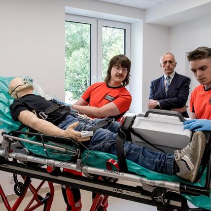 Grupa medycznych profesjonalistów i instruktorów uczestniczy w szkoleniu z wykorzystaniem manekina na leżaku, w modernizowanej stacji pogotowia w Rudzkiej. (wygenerowano przez AI)
