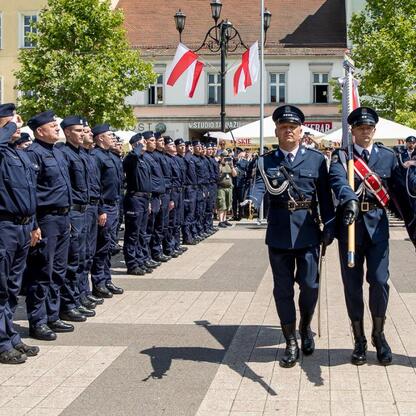 Rybnicki rynek, uroczystości Święta Policji, formacja mundurowa, flaga, sztandar, marszałek Saługa, wojewoda Wójcik, parlamentarzyści, samorządowcy, wyróżnienia, ślubowanie, nowi policjanci. (wygenerowano przez AI)