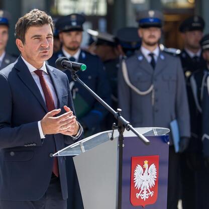 W Rybniku, podczas uroczystości Święta Policji, marszałek Wojciech Saługa przemawia na podium, podczas gdy policjanci w mundurach stoją w szeregach. (wygenerowano przez AI)