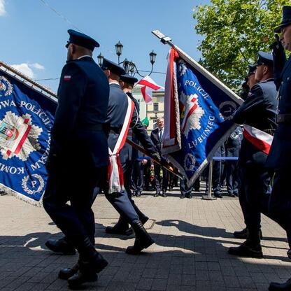Ceremonialny przemarsz policjantów z flagami na Rybnickim rynku, uczczenie zaangażowania i bezpieczeństwa. (wygenerowano przez AI)