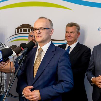 Wojciech Saługa, Marszałek Województwa Śląskiego, przemawia na konferencji prasowej o nowym projekcie infrastrukturalnym w Sławkowie. (wygenerowano przez AI)