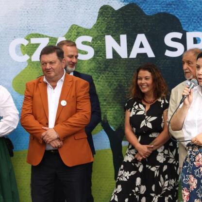 Grupa ludzi ubranych w tradycyjne stroje uczestniczy w Tydzień Kultury Beskidzkiej, festiwalu kultury i tradycji regionu. (wygenerowano przez AI)