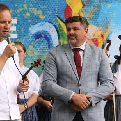 Tydzień Kultury Beskidzkiej: dwaj mówiący na scenie, tło mural i muzyka. (wygenerowano przez AI)