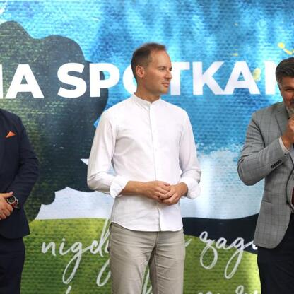 Trzech mężczyzn na scenie podczas konferencji prasowej Tydzień Kultury Beskidzkiej. (wygenerowano przez AI)