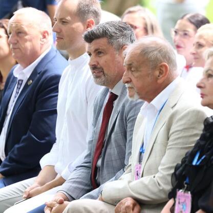 Grupa ludzi w formalnym stroju na zewnątrz, uczestnicy Tydzień Kultury Beskidzkiej. (wygenerowano przez AI)