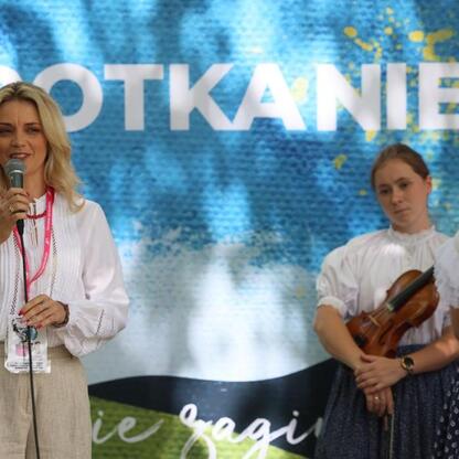 Tydzień Kultury Beskidzkiej: kobieta prowadząca mikrofon, festiwalowy klimat, muzyka i taniec. (wygenerowano przez AI)