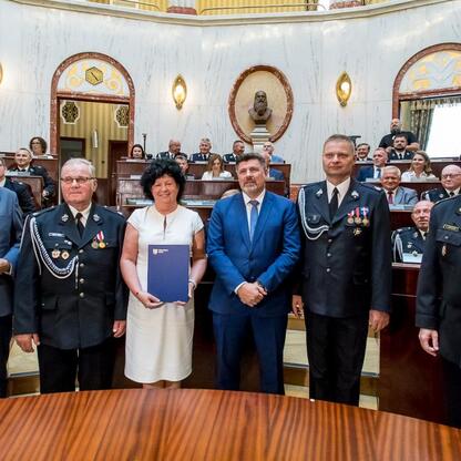 Grupa oficjalna i strażaków na uroczystości dostawy nowych wozów strażackich w regionie Śląskim. (wygenerowano przez AI)