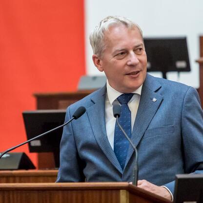 Marszałek Wojciech Saługa przemawia na podium podczas uroczystości prezentacji nowych samochodów ratowniczo-gaśniczych dla OSP w regionie Śląskim. (wygenerowano przez AI)