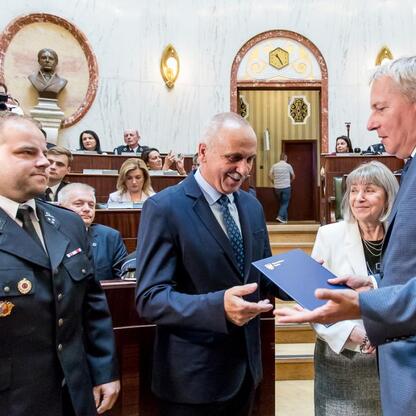 Marszałek Wojciech Saługa wręcza certyfikat na uroczystości dla nowych samochodów ratowniczo-gaśniczych dla OSP w regionie Śląskim. (wygenerowano przez AI)