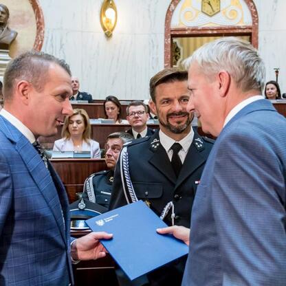 Uroczystość wręczenia dokumentu w sali rządowej, związana z dostawą nowych wozów ratowniczo-gaśniczych dla OSP w regionie Śląskim. (wygenerowano przez AI)