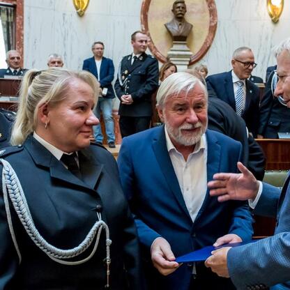 Marszałek Wojciech Saługa wręcza dokument na ceremonii dostawy nowych wozów strażackich. (wygenerowano przez AI)
