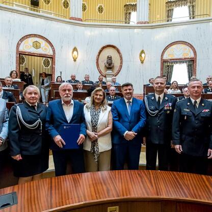 Wojciech Saługa, Marszałek Województwa Śląskiego, i Rafał Adamczyk, Członek Zarządu Województwa Śląskiego, uczestniczą w ceremonii dostarczenia obietnic finansowania 33 nowych wozów strażackich dla OS (wygenerowano przez AI)