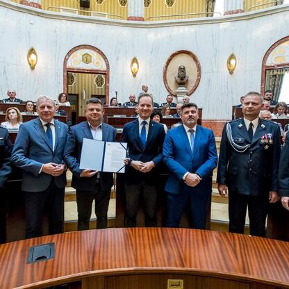 Wojciech Saługa i Rafał Adamczyk uczestniczą w ceremonii wręczenia certyfikatów, podczas której odbiorcami nowych wozów strażackich są OSP w regionie Śląskim. (wygenerowano przez AI)