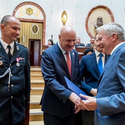Wojciech Saługa, Marszałek Województwa Śląskiego, wręcza dokumenty podczas uroczystości dostawy nowych samochodów ratowniczo-gaśniczych. (wygenerowano przez AI)