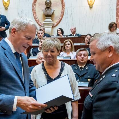 Marszałek Wojciech Saługa wręcza dokumenty w ceremonii dostarczenia nowych samochodów ratowniczo-gaśniczych dla OSP w regionie Śląskim. (wygenerowano przez AI)