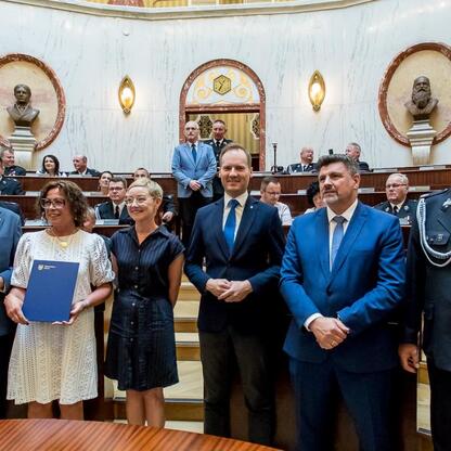 Uroczystość wręczenia certyfikatów w grandowym pomieszczeniu z marszałkiem Wojciechem Saługą i członkiem Zarządu Województwa Rafałem Adamczykiem. (wygenerowano przez AI)