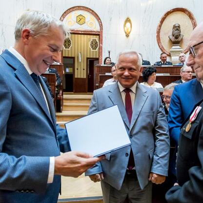 Marszałek Wojciech Saługa wręcza dokument na ceremonii finansowania nowych wozów strażackich. (wygenerowano przez AI)