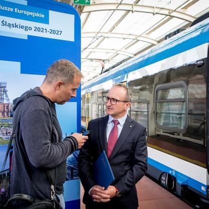 Grzegorz Boski, wicemarszałek Województwa Śląskiego, omawia nowe pociągi Impulsy 2 z Kolejami Śląskimi. (wygenerowano przez AI)