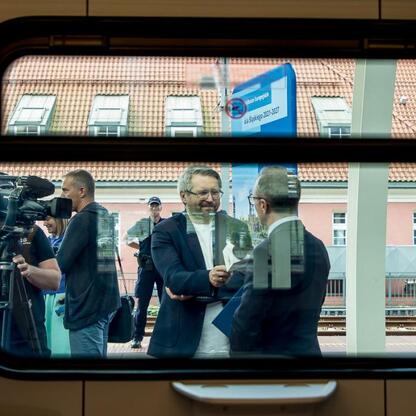Na stacji kolejowej w Śląsku, przedstawiciele lokalnych władz i przedstawiciele przewoźnika omawiają nowe pociągi Impuls 2. (wygenerowano przez AI)