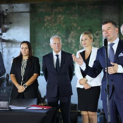Marszałek Wojciech Saługa przemawia na konferencji prasowej w Katowicach, podpisując umowę o dofinansowanie inwestycji w przemysł nowoczesny. (wygenerowano przez AI)