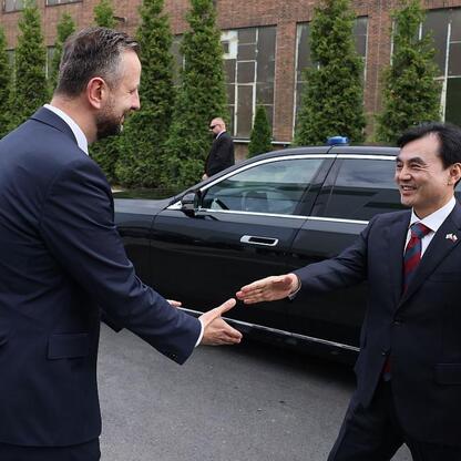 Dwóch mężczyzn w garniturach trzyma się za ręce przed czarnym samochodem, symbolizując rozpoczęcie nowej ery w produkcji czołgów K2 w Polsce. (wygenerowano przez AI)