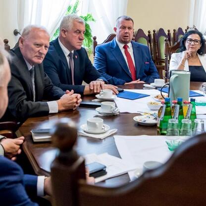 Formalne spotkanie w sali konferencyjnej, gdzie przedstawiciele administracji omawiają projekty scalania gruntów w różnych powiatach województwa śląskiego. (wygenerowano przez AI)