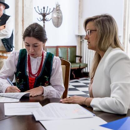 Dwie kobiety prowadzą rozmowę w trakcie ceremonii podpisania umów w ramach Wojewódzkiego Programu - Owca Plus. (wygenerowano przez AI)