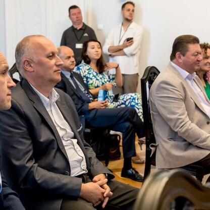 Grupa ludzi w strojach formalnych siedzi w sali, uczestnicząc w ceremonii dotyczącej finansowania projektów turystycznych i kulturalnych w południowej części województwa śląskiego. (wygenerowano przez AI)