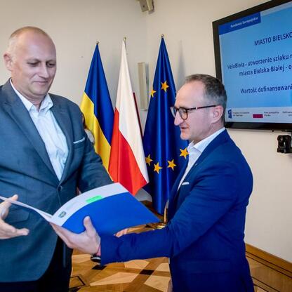 Wicemarszałek Grzegorz Boski wręcza dokumenty przedstawicielom gmin w Sali Błękitnej Gmachu Sejmu Śląskiego. (wygenerowano przez AI)