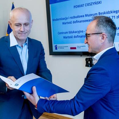 Grzegorz Boski, wicemarszałek województwa śląskiego, wręcza dokumenty przedstawicielom gmin w Sali Błękitnej Gmachu Sejmu Śląskiego. (wygenerowano przez AI)