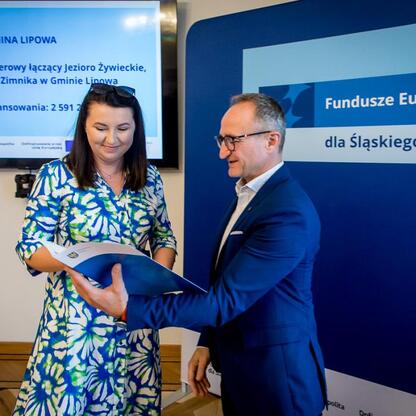 Wicemarszałek Grzegorz Boski wręcza dokumenty przedstawicielce Lipowej w ramach projektu Funduszy Europejskich dla Śląska 2021-2027. (wygenerowano przez AI)