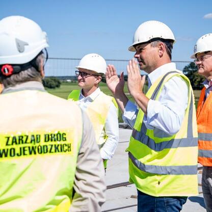 Grzegorz Boski, wicemarszałek województwa śląskiego, omawia z pracownikami budowlanymi postępy w budowie mostu na Odrze w Raciborzu. (wygenerowano przez AI)