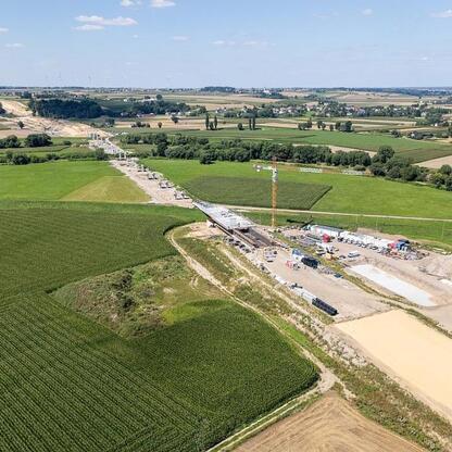 Nowy most na Odrze w Raciborzu w trakcie budowy, z widocznymi kranami i maszynami. Oczekuje się ukończenia w styczniu 2027 roku. (wygenerowano przez AI)
