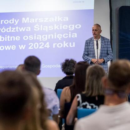 Wicemarszałek Województwa Śląskiego Leszek Pietraszek przemawia na podium podczas uroczystości wręczenia Nagród Marszałka Województwa Śląskiego. (wygenerowano przez AI)