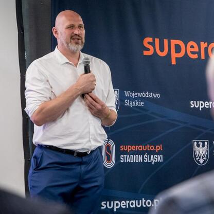 Mężczyzna przemawia na podium podczas uroczystości wręczenia nagród sportowcom w Superauto.pl Stadion Śląskim. (wygenerowano przez AI)