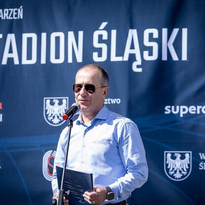 Na Superauto.pl Stadionie Śląskim, przed Silesia Marathon, mężczyzna w niebieskiej koszuli gotowy do wystąpienia. (wygenerowano przez AI)