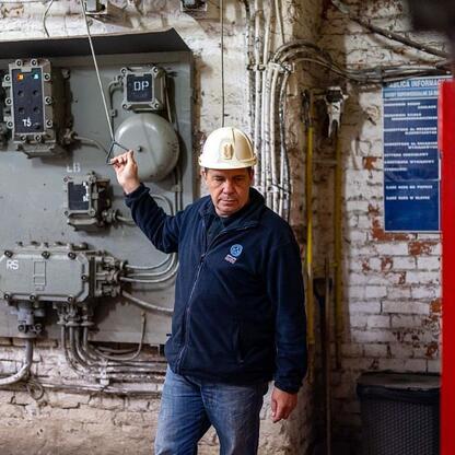 Mężczyzna w mundurze górniczym inspektuje panel elektryczny w muzeum węglowym. (wygenerowano przez AI)