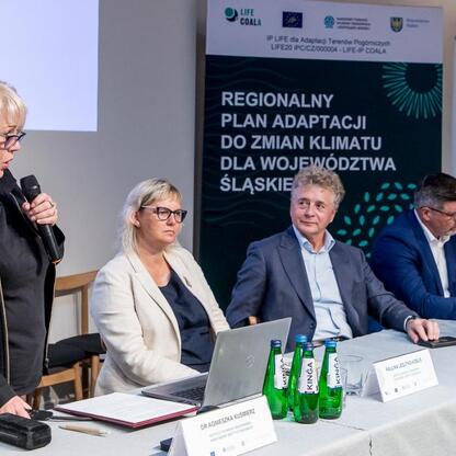 Panel dyskusyjny w Centrum Ekologii i Zieleni w Czechowicach-Dziedzicach, gdzie lokalni urzędnicy i ekspertowie omawiają strategie adaptacji do zmian klimatu. (wygenerowano przez AI)