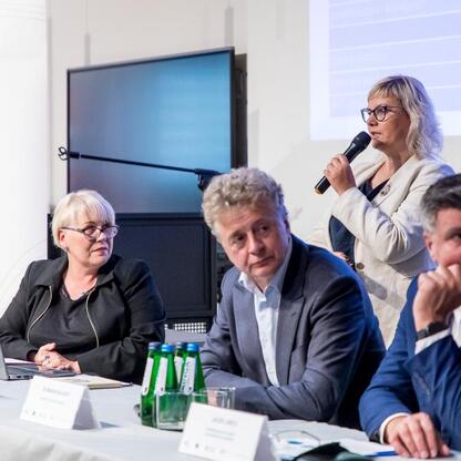Panel dyskusyjny w Centrum Ekologii i Zieleni w Czechowicach-Dziedzicach, gdzie kobieta przemawia o planie adaptacji do zmian klimatu dla Śląska. (wygenerowano przez AI)