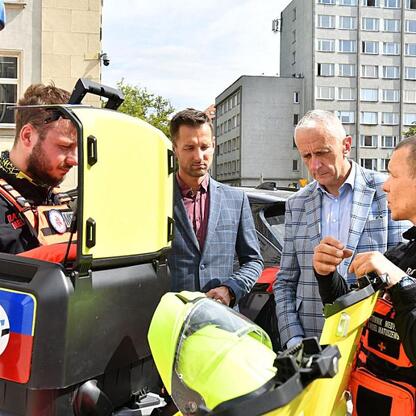 Wicemarszałek Leszek Pietraszek i radny Sejmiku Adam Lubas omawiają nowy motocykl Motoambulans BMW R1300GS, który wchodzi w skład Wojewódzkiego Pogotowia Ratunkowego w Katowicach. (wygenerowano przez AI)