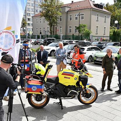 Wicemarszałek Leszek Pietraszek i radny Sejmiku Adam Lubas uczestniczą w przekazaniu nowego motoambulansu dla Wojewódzkiego Pogotowia Ratunkowego w Katowicach. (wygenerowano przez AI)