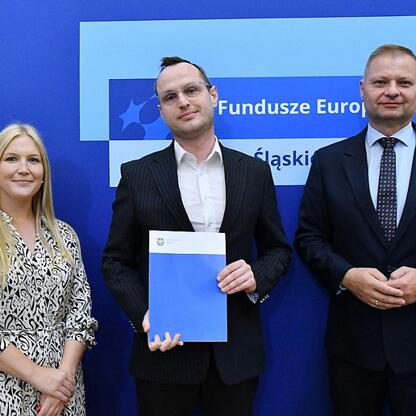 Członkowie Zarządu Województwa Śląskiego Rafał Adamczyk i Joanna Bojczuk wręczają nagrody w ramach programu Fundusze Europejskie dla Śląskiego 2021-2027. (wygenerowano przez AI)