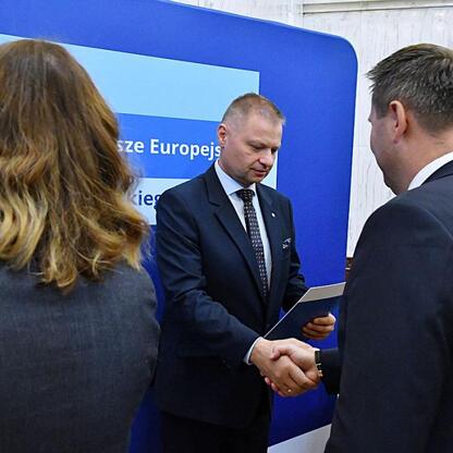 Rafał Adamczyk, członek Zarządu Województwa Śląskiego, wręcza gratulacje podczas ceremonii wsparcia edukacji zawodowej. (wygenerowano przez AI)