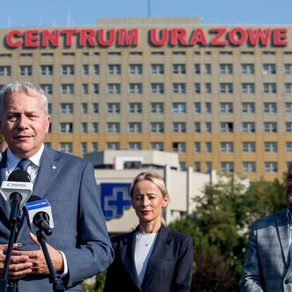 Wojciech Saługa, Marszałek Województwa Śląskiego, prowadzi spotkanie z prezydentem Sosnowca i radnymi miejskimi, omawiając transfer terenu dla szpitalnego helipadu. (wygenerowano przez AI)